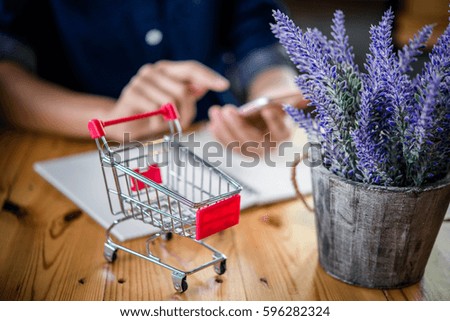 Red shopping cart and laptop on wooden table,shopping online concept.