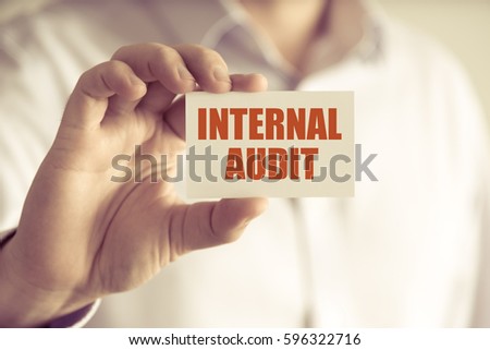 Closeup on businessman holding a card with text INTERNAL AUDIT, business concept image with soft focus background and vintage tone