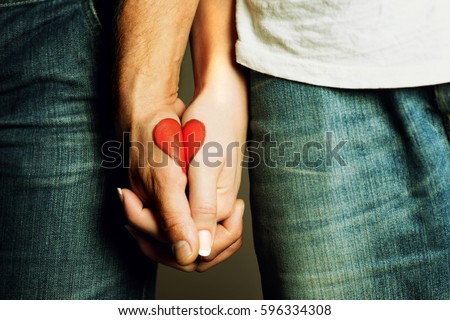 red heart drawing on hands of a couple holding hand in hand, lovers, symbol of love, togetherness, hands holding, love, valentine Royalty-Free Stock Photo #596334308