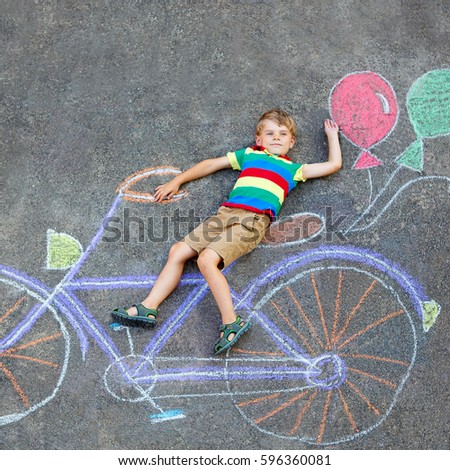 Happy little kid boy having fun with bicycle and air balloons picture drawing with colorful chalks on ground. Children, lifestyle, fun concept. funny child playing and dreaming of future