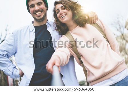 Joyful and happy man and woman posing with a selfie stick on the street