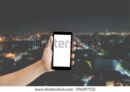 Hand with mobile phone on blurry city at night background