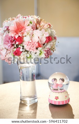 Wedding and love concept in Thailand - Wedding flowers bouquet decoration on table with Snow globe a lovely couple doll ,wedding bride and groom couple doll.