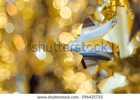 Silver star is hanging on background of golden bokeh