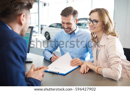 Customers signing contract at car dealer shop 