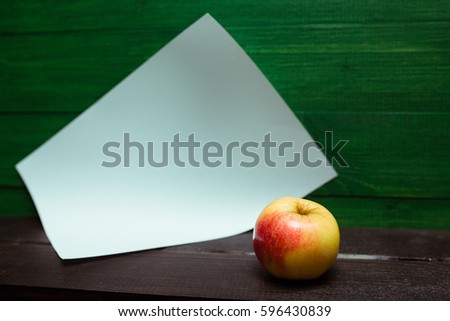 apple with white paper on black shelf and green backgraund 
