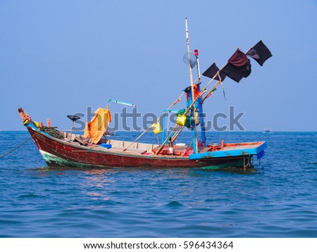 one red fishing boat decorated with flags floating on the blue sea on sunny day 