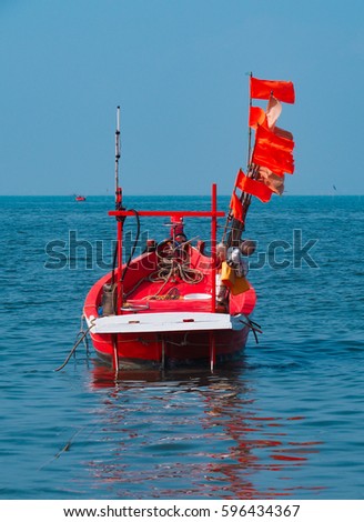 red fishing boat decorated with flags floating on the blue sea on sunny day 