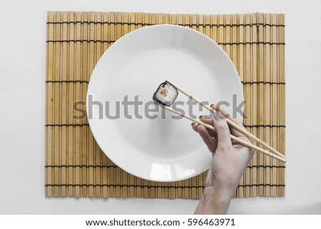 Roll of sushi on a plate, Sushi roll on a tablet, white background, Sushi roll and hand with chopsticks. Japanese food