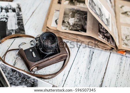 Vintage film camera and family album on the white wooden background among old family photos