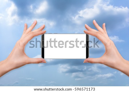 female holding a smartphone isolated blank screen with two hands on a dark storm cloud before rain, ready for snap a picture