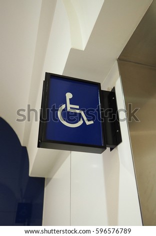 Real toilet sign or restroom direction tab and hanging on the wall and blue color and white icon.