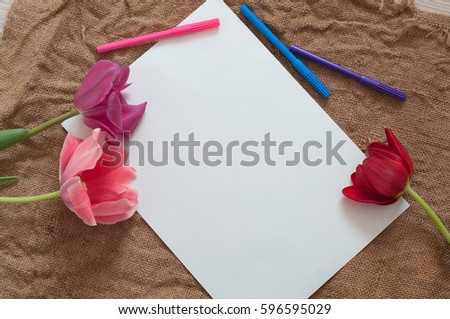 Two empty papers sheet, two tulip and color pens on sackcloth texture