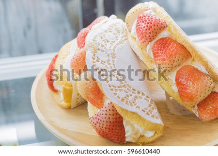 Puff cake white cream with strawberry on wood disk in a cake cabinet