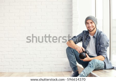 Handsome young photographer sitting on window sill
