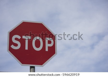 Stop sign - Red with white text with blue sky and clouds in backgournd Irish Road Signs
