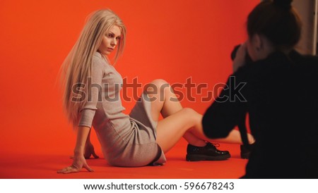 Fashion backstage: blonde girl model plays long hair - photographer take a picture in studio