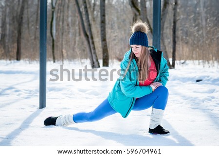 Beautiful young girl stretches on a sports field in winter against a background of deciduous forest.  sports concept photo