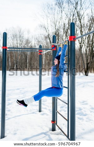 Beautiful young girl doing stretching, fitness on a sports field in winter against a background of deciduous forest.  sports concept photo