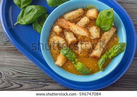 Pumpkin and carrot soup with basil on  wooden background. Top view.