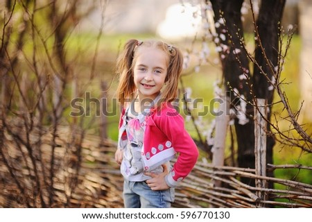 Baby girl without teeth in pink clothes on a background of flowering trees