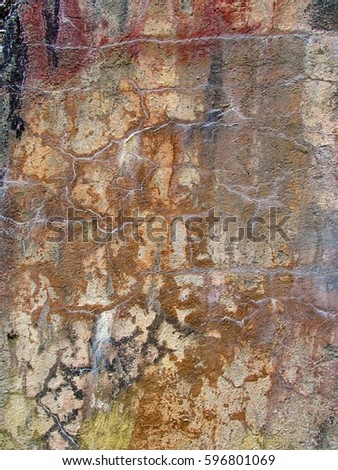 Close-up of a cracked, rusty and multicolored concrete wall. Grunge abstract texture of an old ruined cement surface. Prominent red and black stains. Vertical background photo.