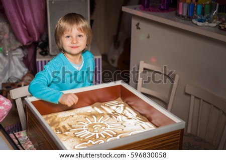 A little boy draws in the sand, sand animation, sand pours from his hands