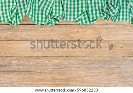 Rustic green checkered table cloth on wood background.