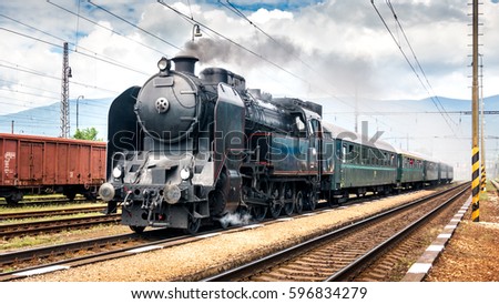 Train with a steam locomotive coming to the railway station. Royalty-Free Stock Photo #596834279