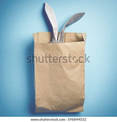 Easter bunny in a paper bag. Rabbit. Blue background. Space for text. Toned image. Trendy toning.