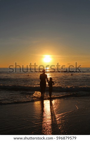 Silhouette of a father and a child working on the beach