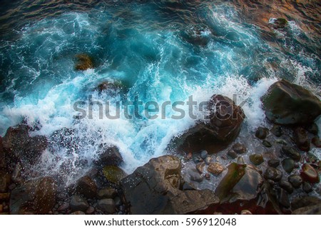 Blue raging waves crashing on the rocks