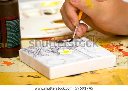 Hands of the young artist of the miniature painter drawing a picture.Work of the artist.