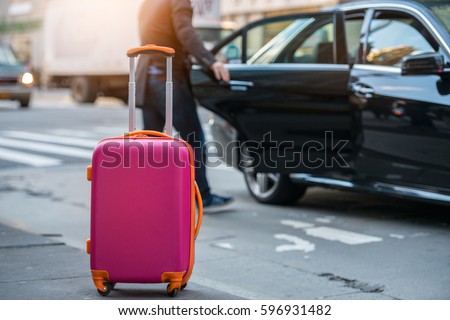 People taking taxi from an airport and loading carry-on luggage bag to the car. Luggage on the city street. Travel concept. Royalty-Free Stock Photo #596931482