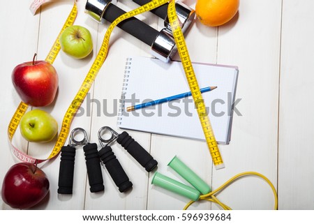Heart, dumbbells and fruits, apples, oranges on a white wooden background