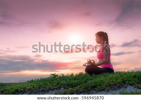 Healthy woman doing Yoga exercises on the beach in sunset morning at Phuket, Thailand