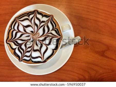 Hot latte in white cup on wood background