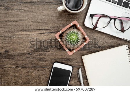 Brown wood office desk table with a book, pen, cactus and phone for working in top view and copy space.