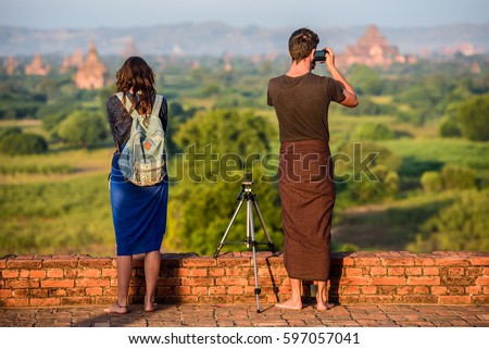 Man takes the photo on the top of the temple in Bagan, Myanmar. Sunrise. Woman beside.