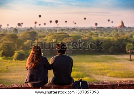Couple watching sunrise over historic Buddhist temples and stupas in Bagan, Myanmar.