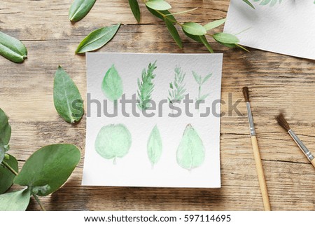 Watercolor painting with leaves on wooden table