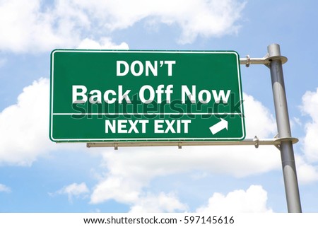 Green overhead road sign with a Don't Back Off Now Next Exit concept against a partly cloudy sky background. 