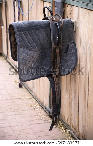 Sporty saddle blanket hanging in a rural barn  Royalty-Free Stock Photo #597189977