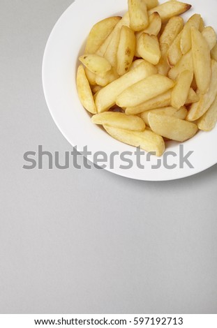 A bowl of French fries on a pale grey background with empty space below