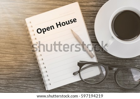 Concept Open House message on notebook with glasses, pencil and coffee cup on wooden table.