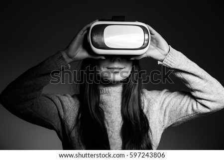 Studio portrait of young girl playing super cool virtual reality glasses for mobile gaming applications.Use mobile apps with innovative 3d vr headset.Trendy augmented reality gamer gadget in use