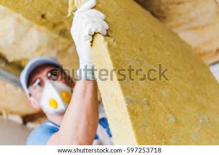 Caucasian Construction Worker with Piece of Insulating Material, Roof Insulating by Mineral Wool. Royalty-Free Stock Photo #597253718