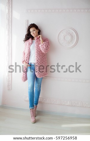Young attractive woman, brunette, with beautiful eyes and snow-white teeth, beautiful smile, in a pink cardigan