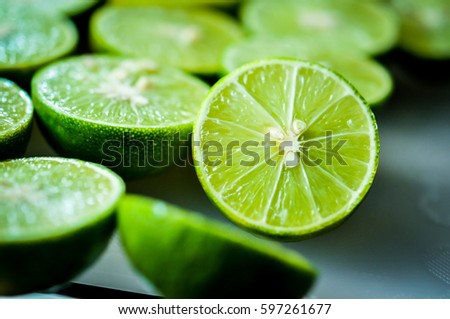 lime Backgrounds, Close up shot, fruit macro photography, Close up sliced of the green limes and seed with a knife place on plastic board in a kitchen. Lime is a kind of fruit. The result is very sour Royalty-Free Stock Photo #597261677