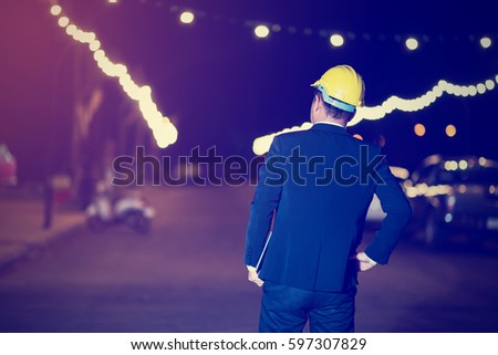 business man in hard hat looking comparing housing project with building with tablet on hand